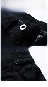 Detail of metal button and reinforced belt loops on black cotton cargo shorts