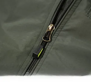 Detailed close-up of premium resin zipper and metal puller on olive outdoor jacket