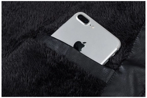 Detail of plush black jacket pocket with leather trim holding a smartphone