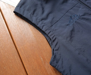 Dettaglio del gilet outdoor blu scuro con ricamo di montagna e tessuto antivento
