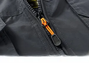 Detail of durable resin zipper with black and orange woven puller on men's utility vest