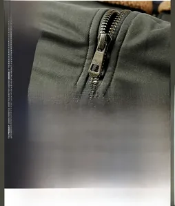Detail of durable olive green fabric and heavy-duty bronze metal zipper on jacket
