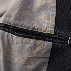 Close-up of black twill denim jacket interior showing grey patterned lining and inner pocket