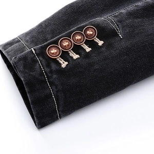 Detail of denim jacket cuff with four decorative brown buttons and white contrast stitching