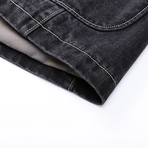 Macro shot of denim jacket pocket detailing with white contrast stitching and printed lining