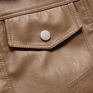 Detailed macro view of a brown leather jacket with flap pocket and silver snap button