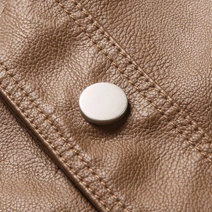 Close-up of brown leather texture with matte silver snap button and reinforced double stitching