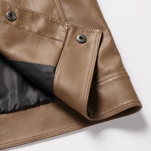 Close-up of brown litchi grain leather jacket with metal snap button and neat stitching