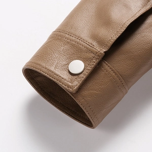 Macro shot of brown leather jacket cuff with lychee texture and silver metal snap button