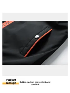 Detail of men's jacket with black fabric, orange webbing, and a metal snap pocket