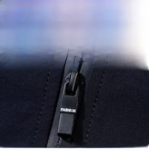 Close-up of matte black zipper pull with FASHION engraving on casual jacket fabric
