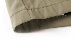 Detailed close-up of khaki outdoor jacket hem showing high-quality double stitching
