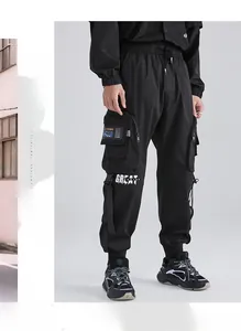 Dettaglio dei pantaloni cargo techwear neri con stampa GREAT DESIGN e cinghie funzionali