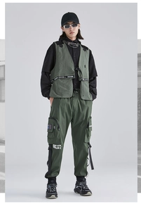 Dettaglio del gilet e pantaloni techwear verde militare con tasche e cinghie tattiche