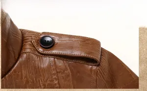 Detail of military-style shoulder strap with black button on brown textured leather jacket