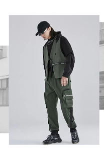 Dettaglio del gilet tattico verde oliva con tasche e pantaloni cargo abbinati