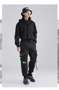 Dettaglio dei pantaloni cargo techwear da uomo con stampa GREAT e tasche tattiche