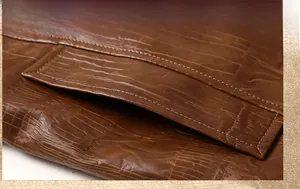 Detail of side pocket on brown faux leather jacket with crocodile texture and stitching