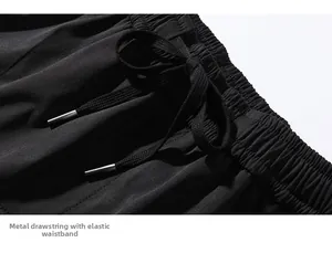 Dettaglio dei pantaloni techwear neri con vita elastica e coulisse con punte in metallo
