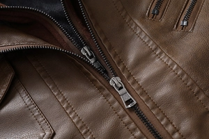 Detailed close-up of brown PU leather jacket featuring metallic zippers and textured grain
