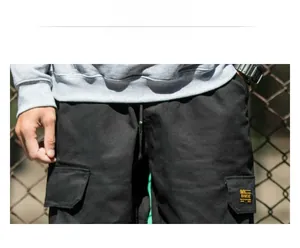 Detailed macro view of large cargo pockets with brand label on black cotton pants