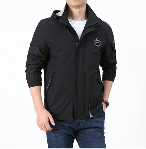 Détail de la veste coupe-vent noire avec logo de montagne et col à capuche pour hommes