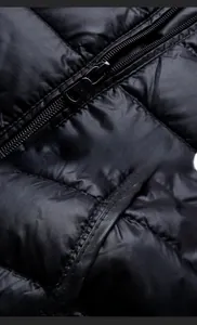 Dettaglio della cerniera in metallo e bordatura premium sul gilet in piumino