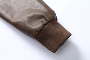 Detail of dark brown leather jacket sleeve featuring elastic ribbed knit cuff texture