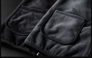 Close-up of black velvet vest fabric featuring symmetrical pockets and metal zipper detail