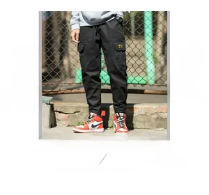 Detail of black cargo pants featuring functional pockets and a yellow brand woven label