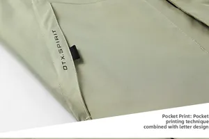 Detail of pocket with black DTX.SPIRIT lettering on light green tactical jacket