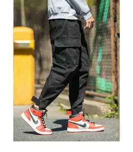 Detail of black cargo pants featuring large side flap pockets and velcro cuffed ankles