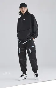 Detail of black techwear cargo pants featuring multi-pocket design and glossy fabric