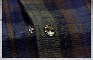 Detail of vintage copper buttons on checked flannel shirt with collection-wear engraving