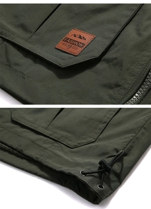 Detail of outdoor vest featuring brown leather fashion patch and adjustable waist drawstring