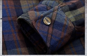 Detail of plaid shirt cuff with vintage bronze button and thick flannel texture