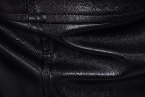Macro shot of premium black leather jacket showing fine grain texture and double stitching
