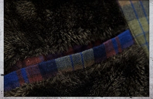 Detailed macro view of the thick warm fleece lining on a plaid flannel hooded shirt