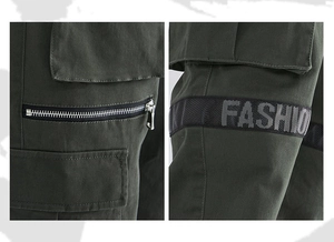 Detail view of dark green cargo pants side pocket with zipper and FASHION woven strap