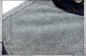 Macro shot of grey heather fabric with navy blue plaid lining on a men's hooded shirt