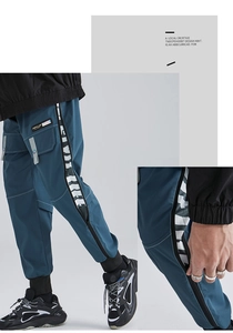 Detail of cargo pants showing functional zipper pockets and street style printed webbing