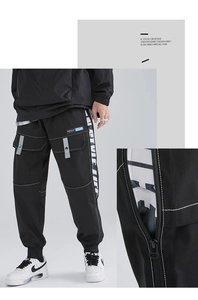 Detail of black techwear cargo pants with contrast stitching and popular label