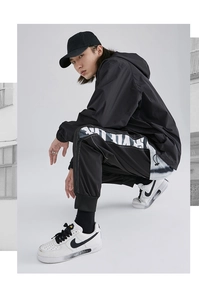Detail of black cargo jogger pants with white gothic font side print and cuffed ankles