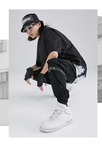 Detail view of black streetwear cargo pants with FASHION ribbon and tactical accessories