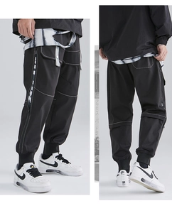 Detail view of black cargo pants featuring white contrast stitching and utility pockets