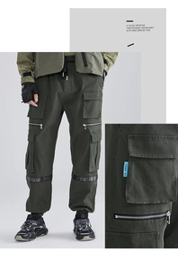Detail of army green cargo pants featuring utility pockets, zippers, and fashion straps