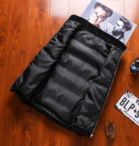 Detailed macro view of black quilted puffer vest showing silver zipper and plush texture