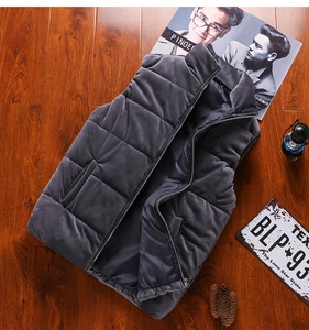 Detailed close-up of dark grey velvet puffer vest with stand collar on vintage wood background