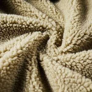 Close-up of thick khaki faux shearling bomber jacket material showing soft texture