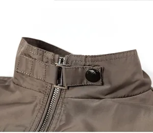 Close-up of dark brown military jacket collar with silver zipper and metal buckle detail